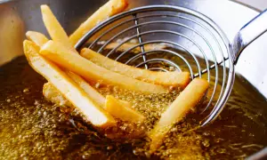 Patatine fritte dorate che sfrigolano nell'olio di oliva, pronte per essere gustate.