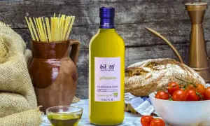 Bottiglia di olio extravergine d'oliva Bilotti, con pasta, pane, pomodorini e una ciotolina di olio, per gustare i migliori tipi di olio.