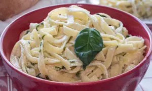 Tagliatelle condite con un delizioso sugo burro e salvia, guarnite con una foglia di basilico fresco.