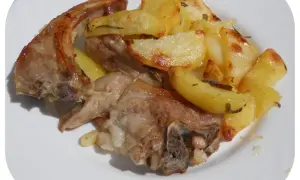 Un succulento agnello gratinato al forno, servito con patate dorate e profumate al rosmarino su un piatto bianco.