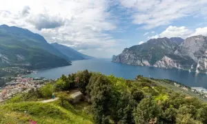 Panoramica mozzafiato del Lago di Garda, ideale per **leichte wanderungen am Gardasee**. Montagne verdi e rocciose incorniciano il blu intenso dell'acqua.