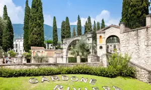 Un'oasi verde a Gardone Riviera, con cipressi svettanti, architetture in pietra e il nome della località inciso sull'erba.