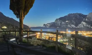 Vista notturna di Riva del Garda, con luci scintillanti e montagne sullo sfondo. Perfetto per scoprire cosa fare la sera.