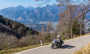 Motociclista in esplorazione dei punti panoramici del Lago di Garda, con montagne imponenti e un lago azzurro sullo sfondo.