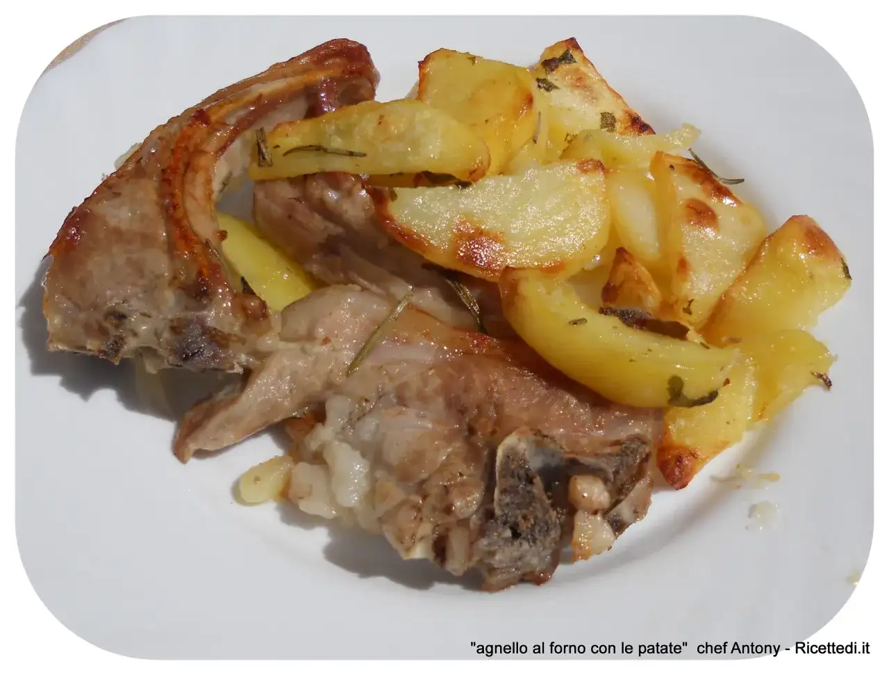 Un succulento agnello gratinato al forno, servito con patate dorate e profumate al rosmarino su un piatto bianco.