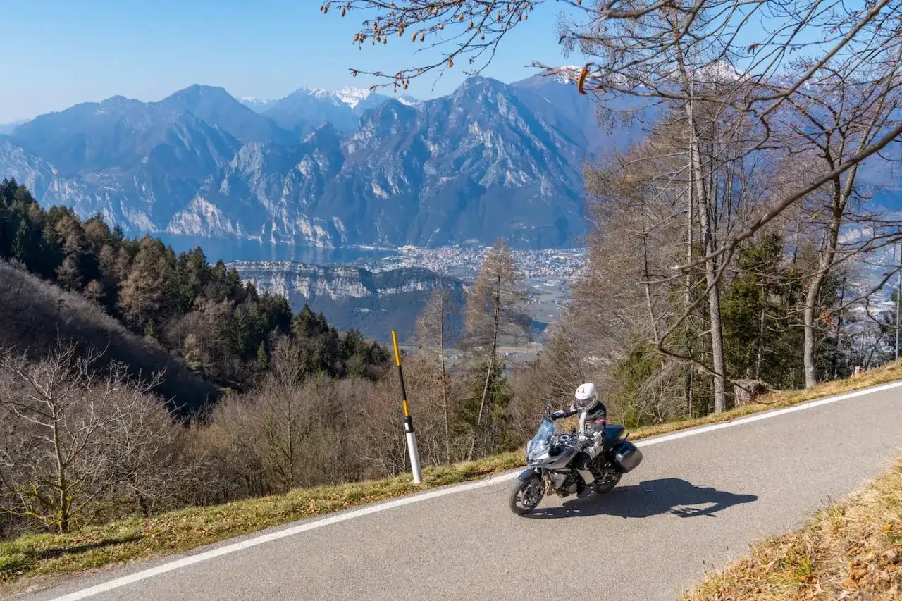 Motociclista in esplorazione dei punti panoramici del Lago di Garda, con montagne imponenti e un lago azzurro sullo sfondo.