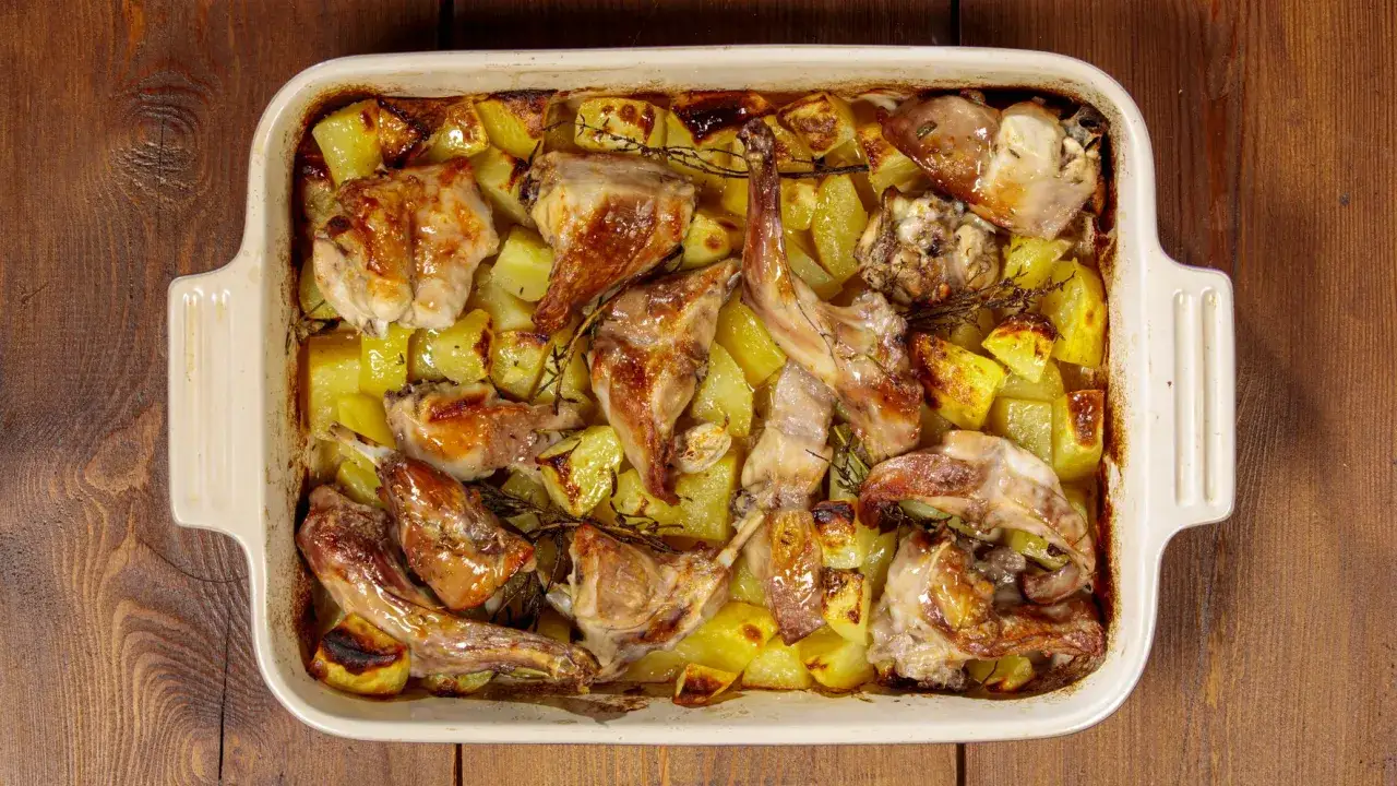 Un saporito coniglio al forno con patate dorate e rosmarino, pronto per essere gustato.
