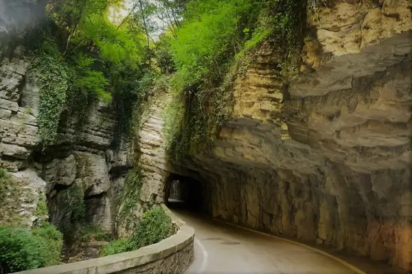 Strada della forra in moto, un percorso suggestivo tra rocce scolpite e vegetazione lussureggiante, con un tunnel che si apre nel verde.