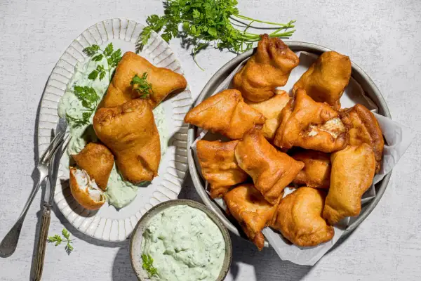 Fritti dorati di lucioperca, perfetti per le tue ricette. Serviti con salsa verde e guarniti con prezzemolo fresco.