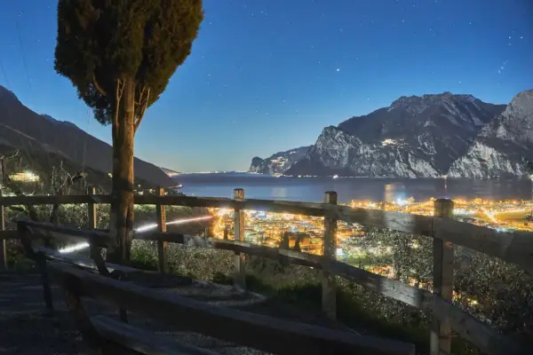 Vista notturna di Riva del Garda, con luci scintillanti e montagne sullo sfondo. Perfetto per scoprire cosa fare la sera.