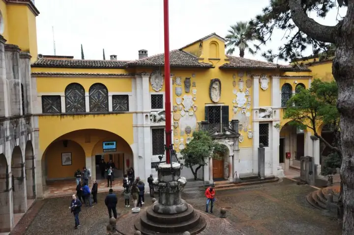 Cortile del Vittoriale degli Italiani, con la facciata gialla decorata da stemmi e sculture. Un luogo affascinante da visitare.
